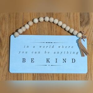 Wooden sign in a world where you can be anything be kind